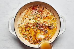 chicken stock and mustard being added to a pan with shallot, garlic and rosemary that were cooked in olive oil