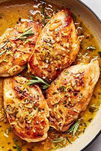 homemade rosemary chicken in a pan with a spoon made with butter, shallots, garlic, rosemary, dijon, lemon juice & zest