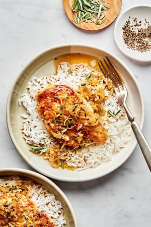 homemade rosemary chicken served on top of white rice on a plate with a fork