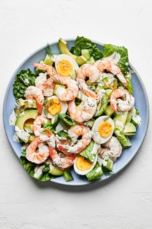 shrimp and avocado salad topped with boiled eggs, homemade dill dressing and flaky salt