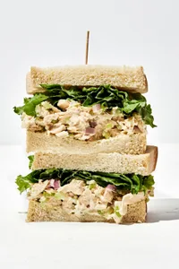 a tuna salad sandwich cut in half and stacked on top of each other with a toothpick sticking out of the top