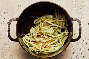 shallots, fennel and salt being cooked in olive oil in a large soup pot