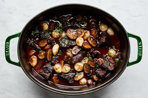 mushrooms and pear onions added to a dutch oven with beef bourguignon