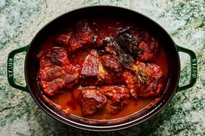 A pot of braised pork ragu made with onion, carrots, celery, tomato sauce, white wine, basil, thyme sage and parsley