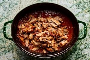A pot of braised pork ragu made with onion, carrots, celery, tomato sauce, white wine, basil, thyme sage and parsley