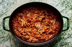 of pot of braised pork ragu made with onion, carrots, celery, tomato sauce, white wine, basil, thyme sage and parsley