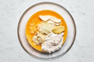 cream of mushroom soup, mayonnaise, mustard, grated onion, onion powder, and eggs. being mixed in a bowl