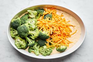 broccoli, cheese and cream of mushroom soup sauce being combined in a baking dish