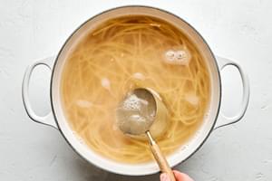 bucatini pasta noodles cooking in a pot of hot water