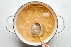 bucatini pasta noodles cooking in a pot of hot water