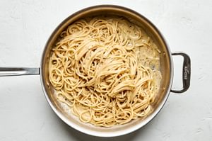 a pan of cacio e pepe made with bucatini, olive oil, butter, pepper, Romano and Parmesan