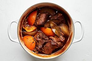 cooked carnitas in a dutch oven made with chicken stock, orange & lime juice, onion & spices