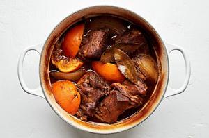 cooked carnitas in a dutch oven made with chicken stock, orange & lime juice, onion & spices