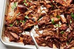 homemade carnitas on a baking sheet seasoned with bay leaves, oregano, chili powder, salt, cumin, pepper & cayenne