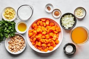 carrots, onion, garlic, ginger, stock, spices, coconut milk, cilantro and macadamia nuts in prep bowls