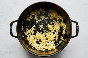 onion and garlic being cooked in olive oil in a soup pot