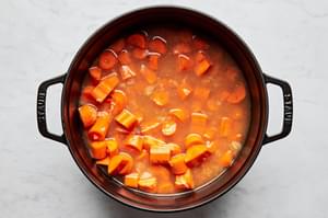 carrots, spices and onion cooking in vegetable stock in a soup pot