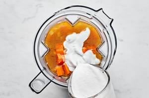 carrot ginger soup being blended in a blender with coconut milk