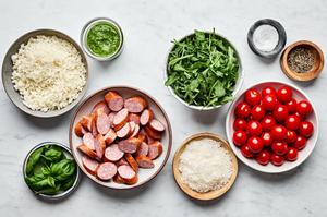 Cauliflower Rice, smoked sausage, pesto, cherry tomatoes, arugula, basil, salt & pepper in prep bowls