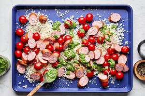 cauliflower rice, smoked sausage, tomatoes, pesto, salt & pepper being tossed together on a sheet pan
