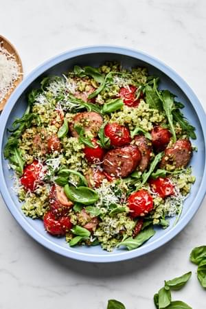Cauliflower Rice Sheet Pan in a bowl made with smoked sausage, pesto, tomatoes, arugula, basil and topped with Parmesan