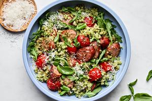 Cauliflower Rice Sheet Pan in a bowl made with smoked sausage, pesto, tomatoes, arugula, basil and topped with Parmesan