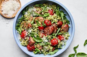 Cauliflower Rice Sheet Pan in a bowl made with smoked sausage, pesto, tomatoes, arugula, basil and topped with Parmesan