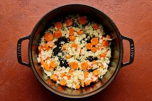 onion and carrot being cooked in olive oil in a soup pot