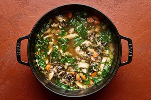 a pot of chicken and wild rice soup made with carrots, garlic, ginger, onion, and spinach