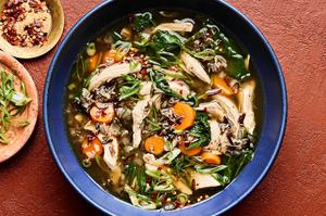 a bowl of chicken and wild rice soup made with carrots, spinach, garlic, ginger, spinach & green onions