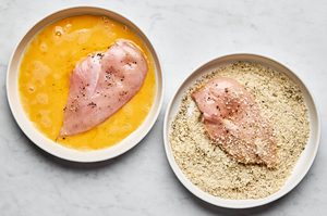 chicken breasts seasoned with salt and pepper being dipped into an egg wash then coated in panko and italian seasoning