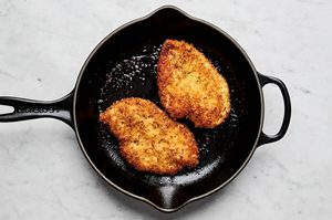 chicken milanese breaded with panko and italian seasoning being cooked in a skillet