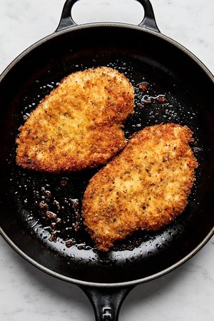 chicken milanese breaded with panko and italian seasoning being cooked in a skillet