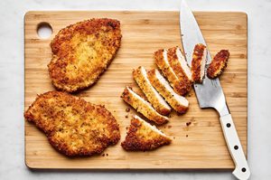 chicken milanese seasoned with italian seasoning and breaded with panko being sliced on a cutting board
