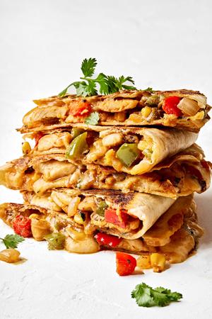 a sliced quesadilla stacked on a plate made with bell peppers, onion, corn and spices