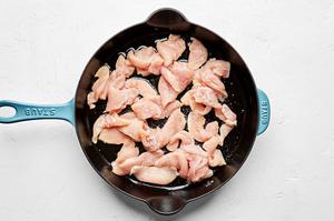 chicken seasoned with salt being cooked in olive oil in a skillet