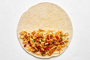 chicken filling being placed on a flour tortilla with cheese