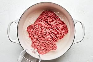 Ground beef being cooked in a soup pot with water
