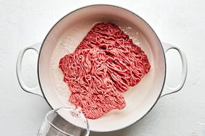 Ground beef being cooked in a soup pot with water