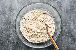 cream cheese, mayo, sour cream spices, Worcestershire, lemon juice, hot sauce, cheese & crab meat being stirred in a bowl