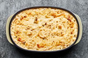 a baking dish of hot crab dip made with cream cheese, mayo, sour cream, spices, white cheddar cheese and mozzarella