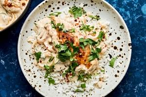 creamy coconut lime chicken in a skillet topped with cilantro, green onions and red pepper flakes served on top of rice