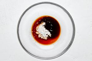 Shaoxing wine, salt, soy sauce, dark soy sauce, and cornstarch being mixed in a bowl