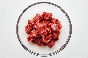 sliced flank steak being tossed with Shaoxing wine, salt, soy sauce, dark soy sauce, and cornstarch