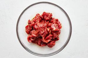 sliced flank steak being tossed with Shaoxing wine, salt, soy sauce, dark soy sauce, and cornstarch