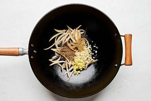 onion, garlic, ginger and peppercorns being cooked in vegetable oil in a skillet