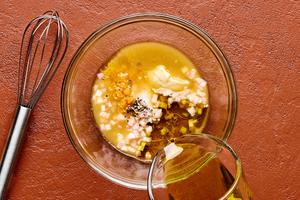 olive oil, white wine vinegar, orange zest, orange juice, honey, dijon, shallots, salt & pepper being whisked in a bowl