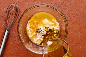 olive oil, white wine vinegar, orange zest, orange juice, honey, dijon, shallots, salt & pepper being whisked in a bowl