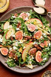 A fig and goat cheese salad made with spinach, arugula, candied pecans, a citrusy dijon vinaigrette, topped with chives