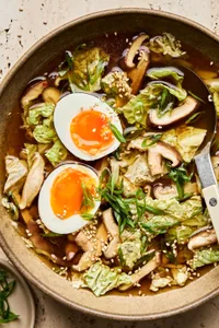 a bowl of gingery vegetable soup made with mushrooms, cabbage, soy sauce & chili paste, topped with boiled eggs